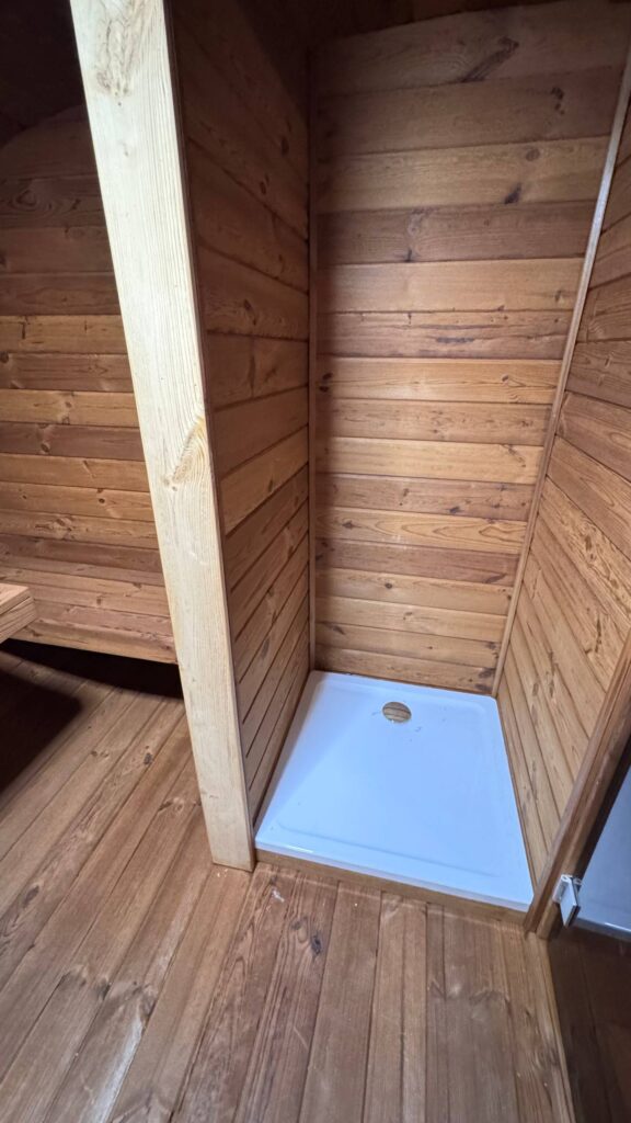 Duschbereich mit Duschwanne im Inneren der Oval Sauna