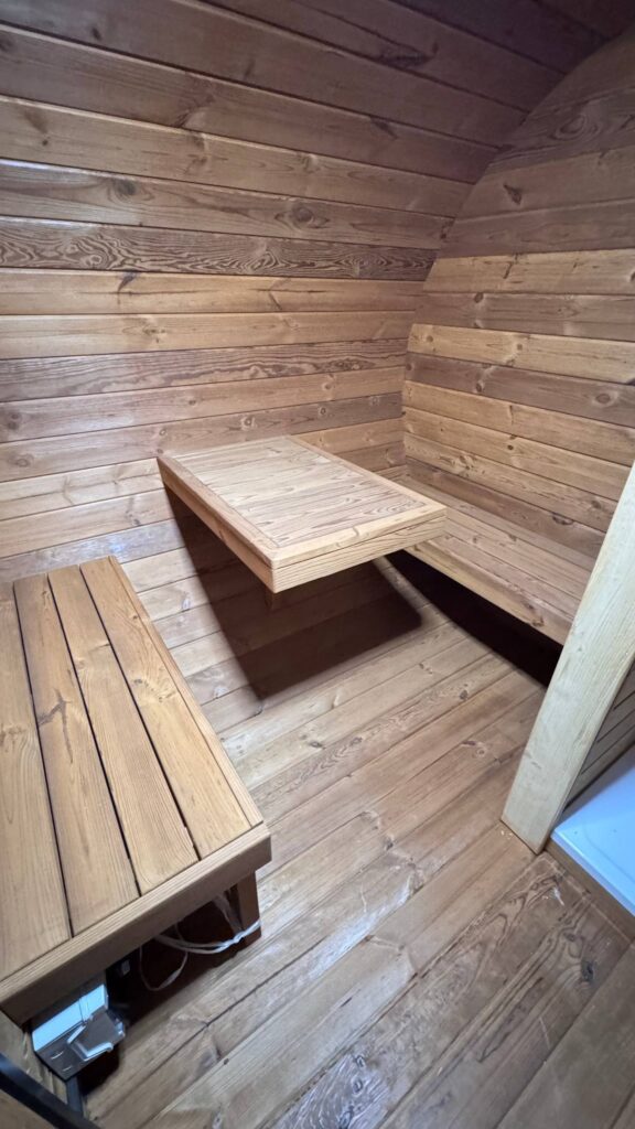 Vorraum der Oval Sauna mit Sitzbänken und Holztisch